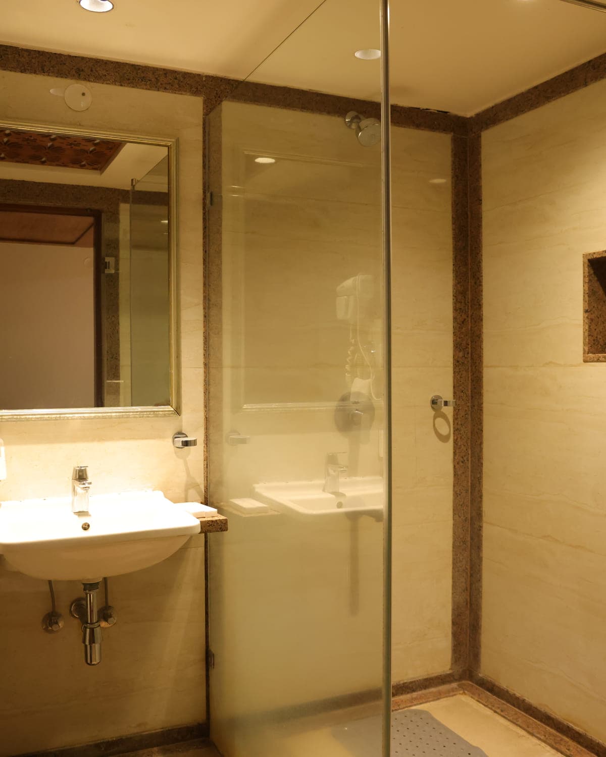 A guest bathroom with a glass shower enclosure and a stone counter