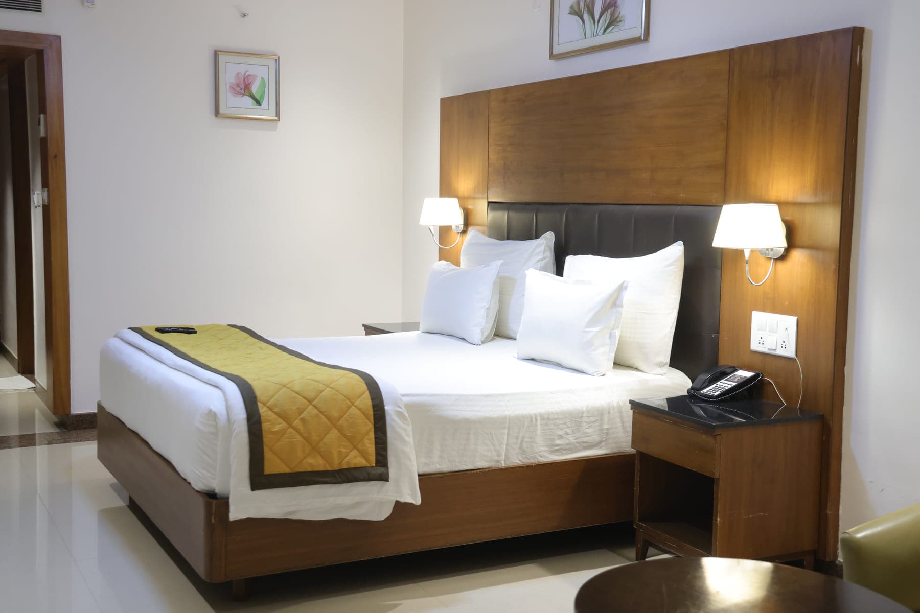The bed in a Deluxe Room, made up with white linen and a gold runner