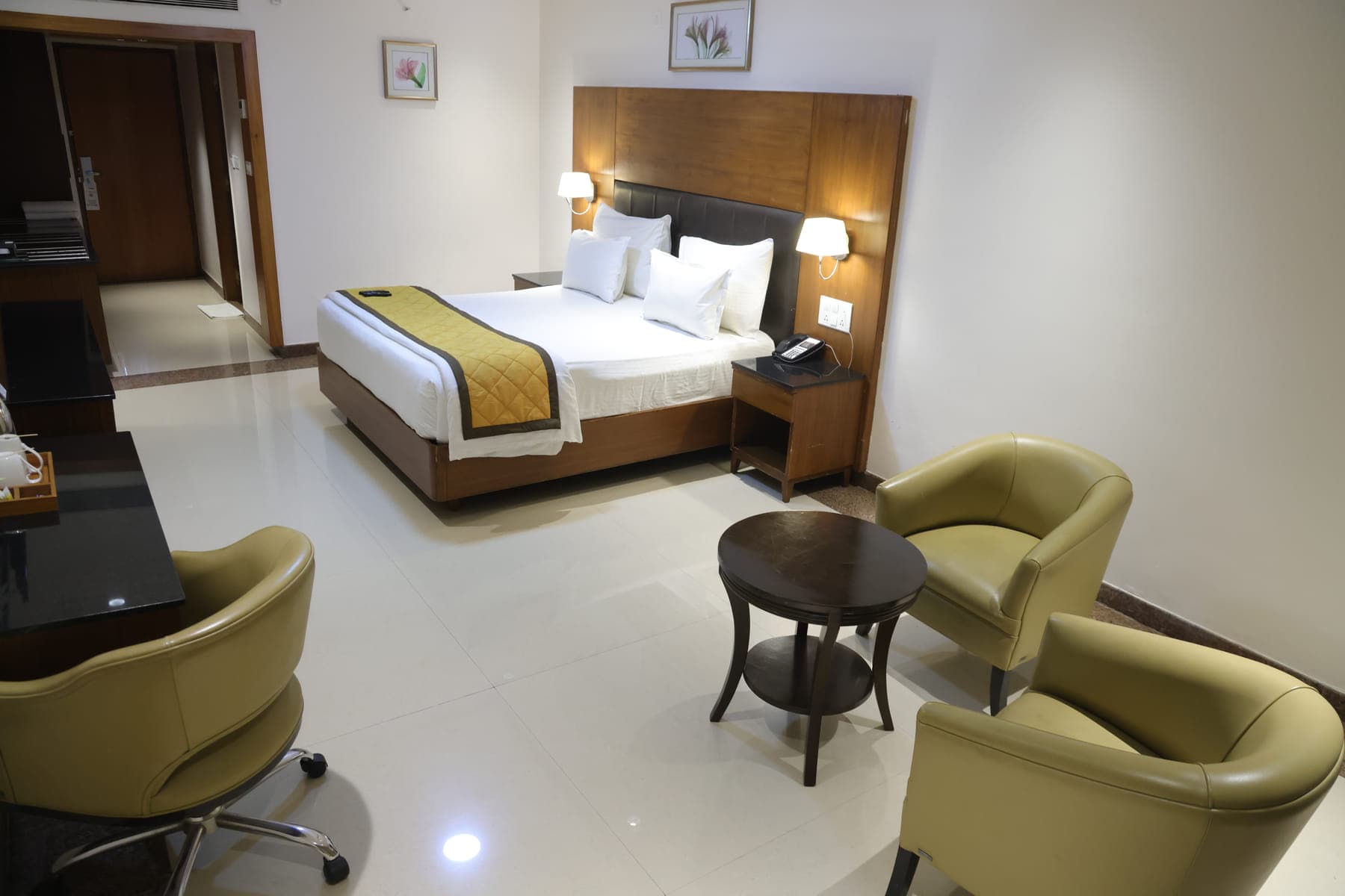 A Deluxe Room with a double bed, a work desk and two armchairs around a low table