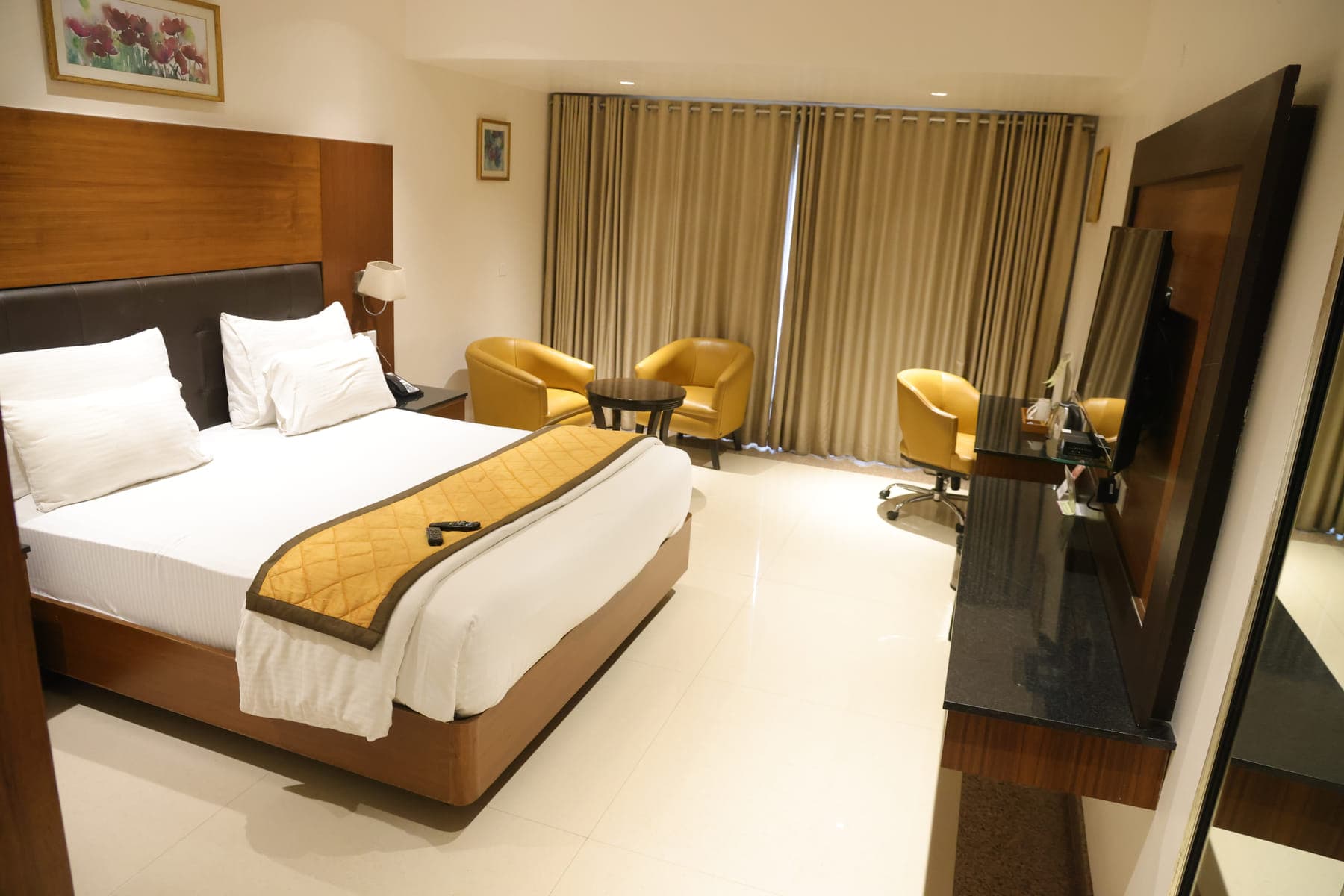A Super Deluxe Room, with floor-to-ceiling curtains and a seating area beside the window